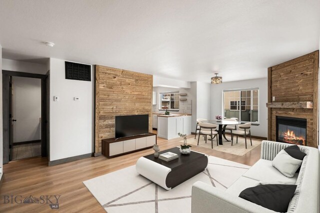 living area featuring light wood-type flooring, baseboards, visible vents, and a fireplace