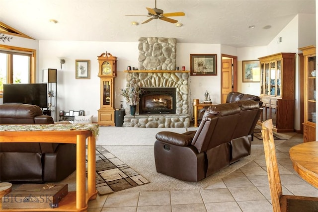 living room with tile patterned flooring, a stone fireplace, a ceiling fan, and lofted ceiling