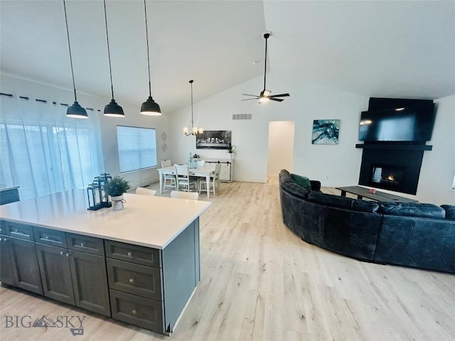 42 Wild Rye Pl, Three Forks, MT 59752 - kitchen featuring light wood-type flooring, a chandelier, a lit fireplace, a ceiling fan, and open floor plan