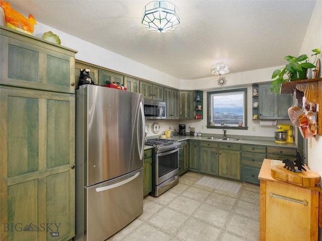 37 Bridger Meadow Ln, Emigrant, MT 59065 - kitchen with stainless steel appliances, green cabinets, a sink, open shelves, and light flooring