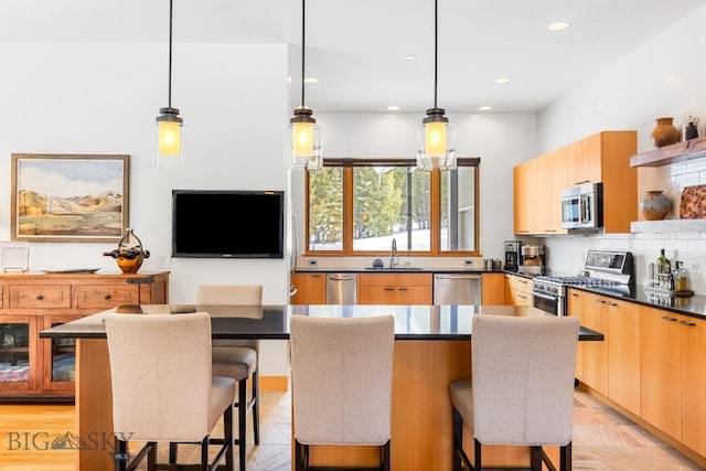 214 W Pine Cone Ter, Big Sky, MT 59716 - kitchen featuring appliances with stainless steel finishes, modern cabinets, dark countertops, a breakfast bar, and light brown cabinetry
