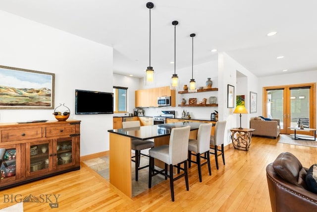 214 W Pine Cone Ter, Big Sky, MT 59716 - kitchen with stainless steel appliances, open shelves, open floor plan, dark countertops, and light wood-style floors