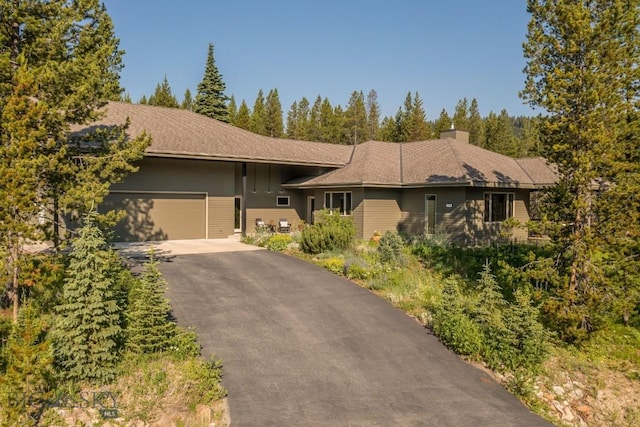 214 W Pine Cone Ter, Big Sky, MT 59716 - view of front of home featuring asphalt driveway, an attached garage, and a chimney