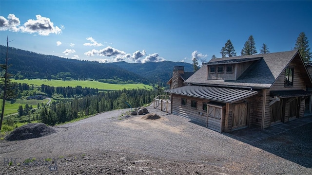 11310 Taiga Trl, Bozeman, MT 59715 - view of property exterior with a standing seam roof, a mountain view, a metal roof, gravel driveway, and a chimney