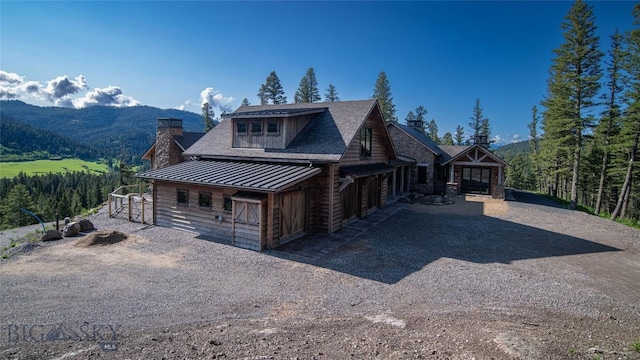 11310 Taiga Trl, Bozeman, MT 59715 - view of front of house featuring a standing seam roof, driveway, a metal roof, a mountain view, and a chimney