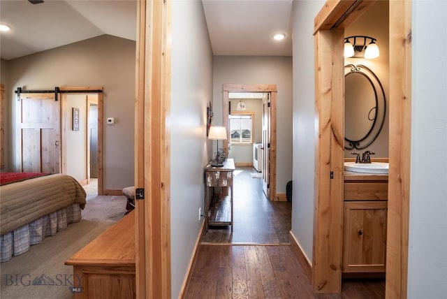 154 Nellie Ct, Manhattan, MT 59741 - corridor with a sink, a barn door, baseboards, dark wood-style flooring, and lofted ceiling
