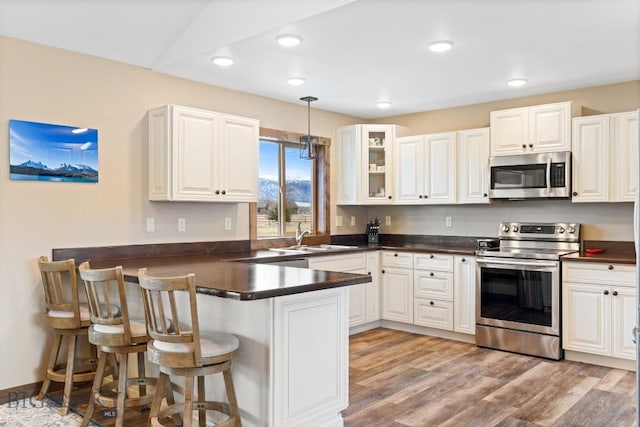 83 Sky Vw, Ennis, MT 59729 - kitchen with appliances with stainless steel finishes, a peninsula, a sink, dark countertops, and recessed lighting