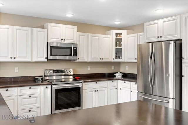 83 Sky Vw, Ennis, MT 59729 - kitchen featuring stainless steel appliances, dark countertops, white cabinetry, and glass insert cabinets