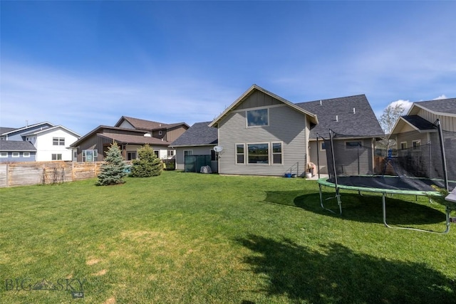 4156 Sunstone St, Bozeman, MT 59718 - rear view of house featuring a trampoline, board and batten siding, fence, and a lawn