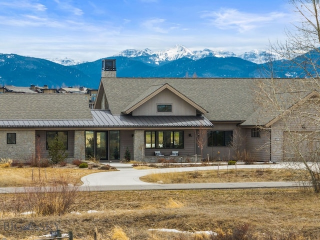676 Tillyfour, Bozeman, MT 59718 - view of front of house featuring a mountain view, a standing seam roof, stone siding, metal roof, and a shingled roof