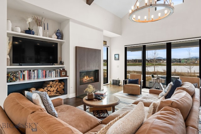 676 Tillyfour, Bozeman, MT 59718 - living room with a water view, a chandelier, wood finished floors, a high ceiling, and a glass covered fireplace