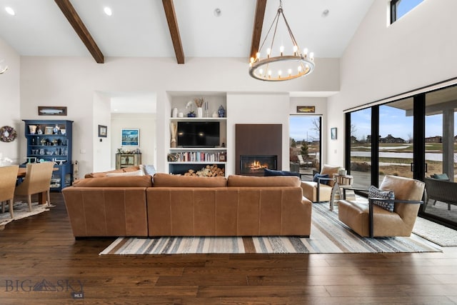 676 Tillyfour, Bozeman, MT 59718 - living room with a chandelier, beamed ceiling, hardwood / wood-style floors, and a warm lit fireplace