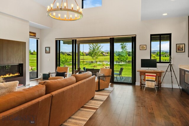 676 Tillyfour, Bozeman, MT 59718 - living room with a high ceiling, a chandelier, dark wood finished floors, plenty of natural light, and a glass covered fireplace