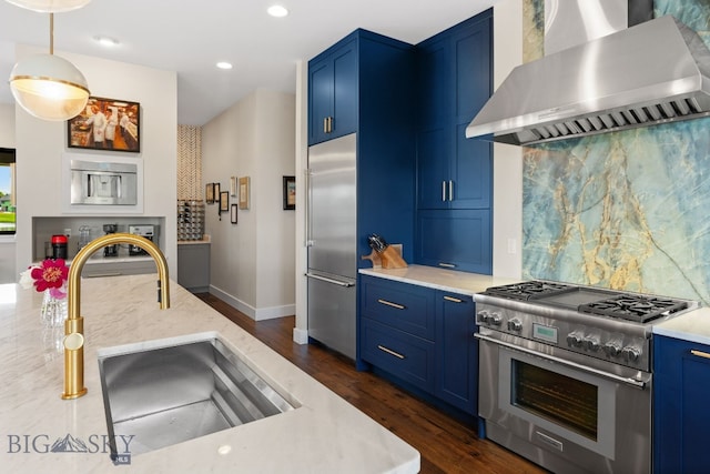 676 Tillyfour, Bozeman, MT 59718 - kitchen with wall chimney range hood, premium appliances, blue cabinets, dark wood-style flooring, and backsplash
