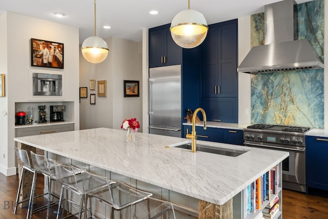 676 Tillyfour, Bozeman, MT 59718 - kitchen featuring wall chimney exhaust hood, premium appliances, blue cabinetry, dark wood-type flooring, and tasteful backsplash
