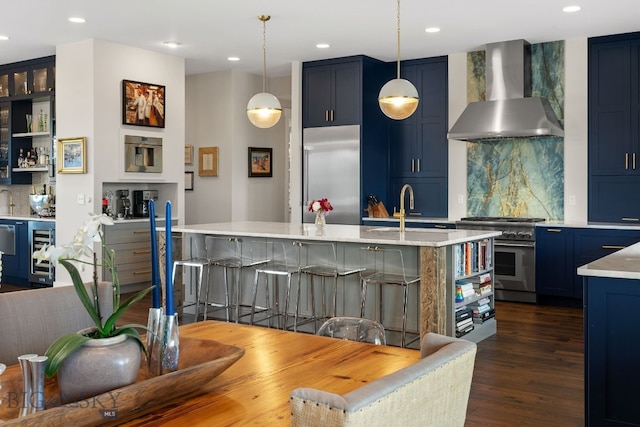 676 Tillyfour, Bozeman, MT 59718 - kitchen featuring premium appliances, wall chimney exhaust hood, wine cooler, blue cabinetry, and tasteful backsplash