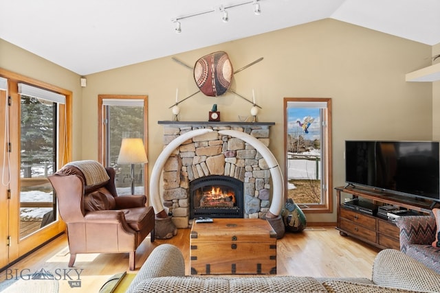 3310 Tumbleweed Dr, Bozeman, MT 59715 - living area featuring wood finished floors, rail lighting, lofted ceiling, and a stone fireplace