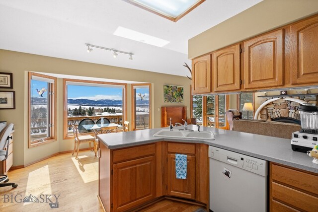 3310 Tumbleweed Dr, Bozeman, MT 59715 - kitchen featuring white dishwasher, a sink, light wood-style flooring, a peninsula, and a mountain view