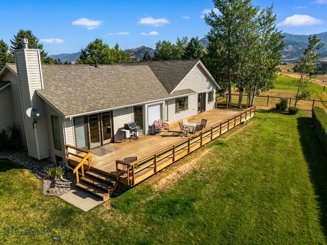 3310 Tumbleweed Dr, Bozeman, MT 59715 - rear view of house with a chimney, a lawn, a fenced backyard, a deck with mountain view, and a shingled roof