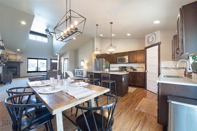 121 Scott Dr, Bozeman, MT 59718 - dining area with high vaulted ceiling, a glass covered fireplace, light wood-style flooring, recessed lighting, and a chandelier
