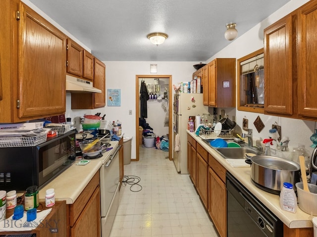 907 Montana St, Belgrade, MT 59714 - kitchen with light countertops, light floors, under cabinet range hood, a sink, and black appliances