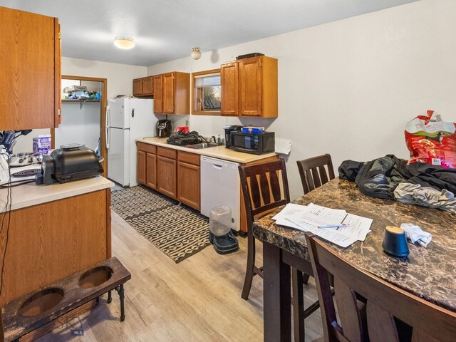 907 Montana St, Belgrade, MT 59714 - kitchen featuring light countertops, light wood-type flooring, white appliances, a sink, and brown cabinets