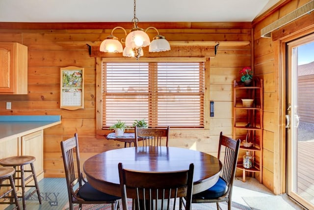 dining space with wood walls and a chandelier