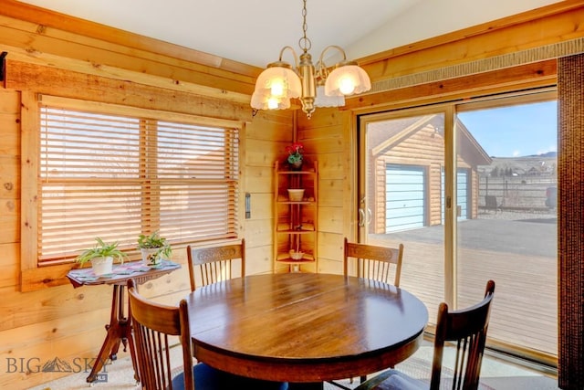 dining space with a chandelier, wooden walls, and lofted ceiling