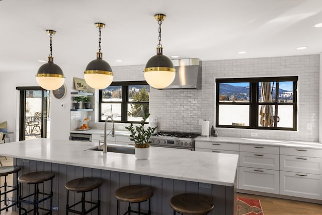 7980 Balsam, Bozeman, MT 59718 - kitchen with high end stainless steel range, wall chimney exhaust hood, a kitchen breakfast bar, light stone countertops, and decorative backsplash