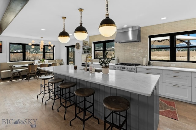 7980 Balsam, Bozeman, MT 59718 - kitchen with wall chimney range hood, gas range, light wood-style flooring, white cabinetry, and recessed lighting
