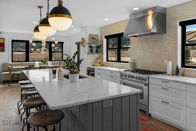 7980 Balsam, Bozeman, MT 59718 - kitchen with stainless steel gas stove, wall chimney exhaust hood, plenty of natural light, a kitchen bar, and recessed lighting