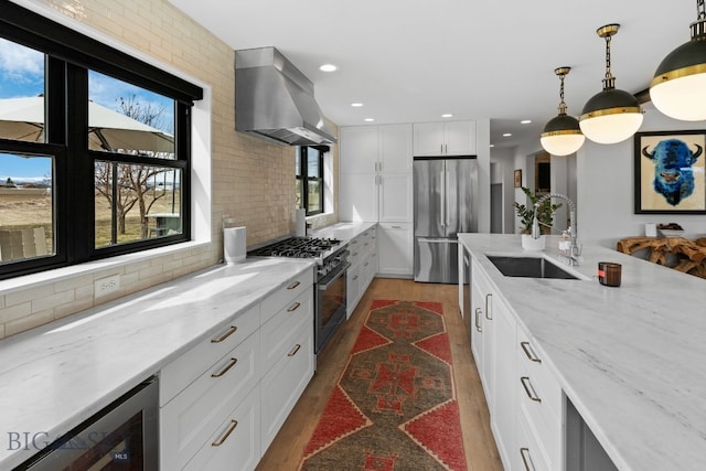7980 Balsam, Bozeman, MT 59718 - kitchen featuring wall chimney range hood, stainless steel appliances, beverage cooler, wood finished floors, and decorative backsplash