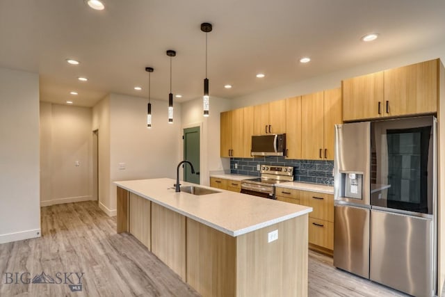1104 Ridgeview Trl, Livingston, MT 59047 - kitchen featuring appliances with stainless steel finishes, light countertops, light brown cabinetry, light wood-type flooring, and a kitchen island with sink