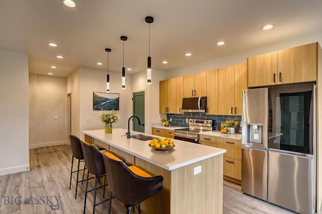 1104 Ridgeview Trl, Livingston, MT 59047 - kitchen featuring appliances with stainless steel finishes, light countertops, an island with sink, light wood-type flooring, and a breakfast bar area