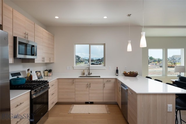 602 Mira Way Unit A, Belgrade, MT 59714 - kitchen featuring light brown cabinets, appliances with stainless steel finishes, a peninsula, a breakfast bar area, and light countertops