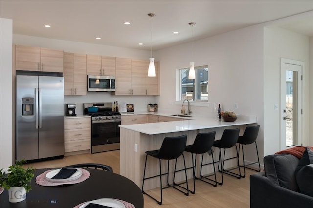 602 Mira Way Unit A, Belgrade, MT 59714 - kitchen featuring appliances with stainless steel finishes, light brown cabinets, light wood-style flooring, a peninsula, and light countertops