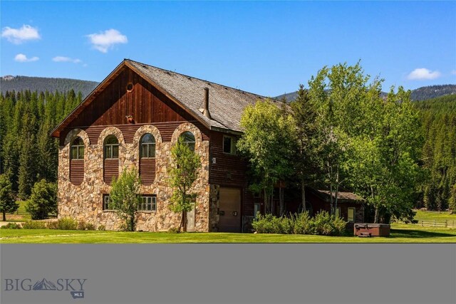 31255 Ninemile Rd, Huson, MT 59846 - tudor house featuring stone siding, an attached garage, a front yard, and a forest view