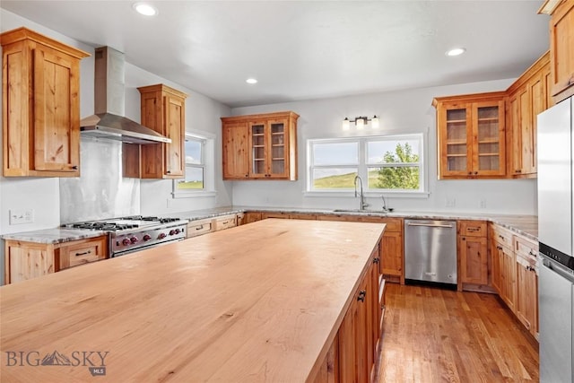 49 Wild Rye Pl, Three Forks, MT 59752 - kitchen with wall chimney exhaust hood, appliances with stainless steel finishes, light wood-style floors, glass insert cabinets, and recessed lighting