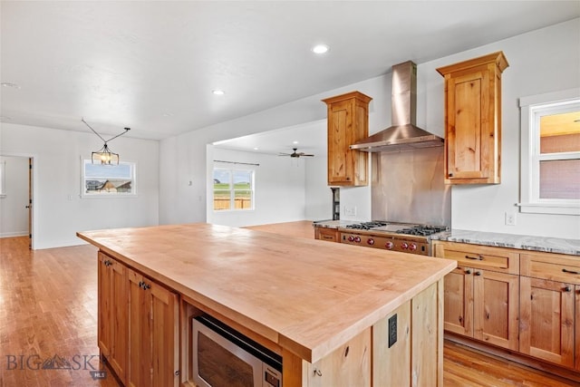 49 Wild Rye Pl, Three Forks, MT 59752 - kitchen featuring wall chimney exhaust hood, appliances with stainless steel finishes, butcher block countertops, light wood-type flooring, and a kitchen island