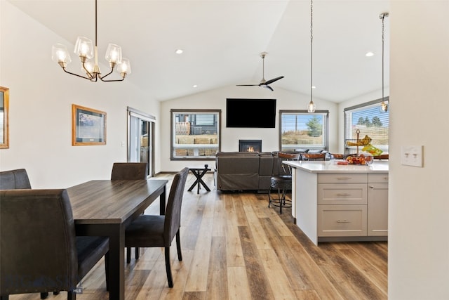 104 Albrey Trl Unit C, Bozeman, MT 59718 - dining space featuring light wood-style flooring, a glass covered fireplace, a ceiling fan, vaulted ceiling, and a chandelier