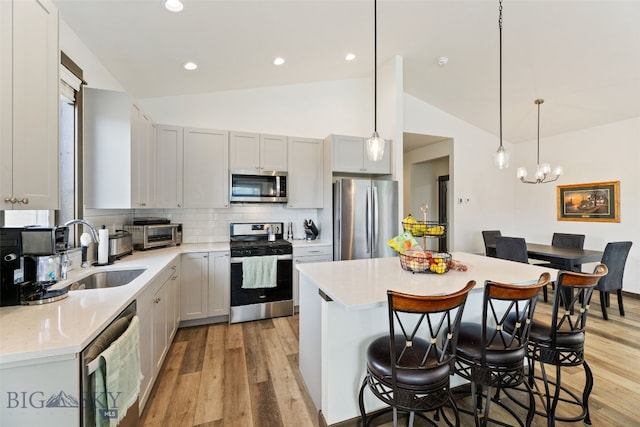 104 Albrey Trl Unit C, Bozeman, MT 59718 - kitchen featuring appliances with stainless steel finishes, light wood-type flooring, a kitchen bar, vaulted ceiling, and light countertops
