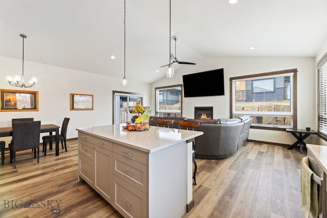 104 Albrey Trl Unit C, Bozeman, MT 59718 - kitchen with lofted ceiling, a glass covered fireplace, wood finished floors, a chandelier, and light countertops