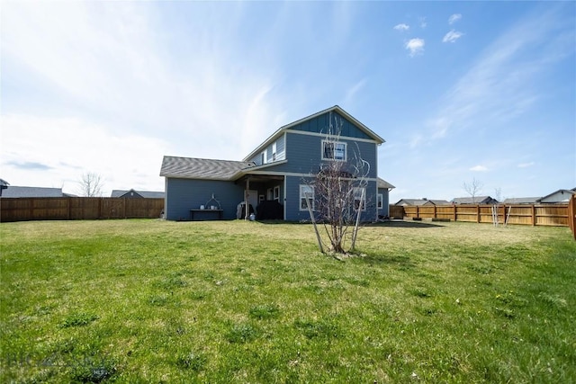 rear view of property featuring a yard and a fenced backyard