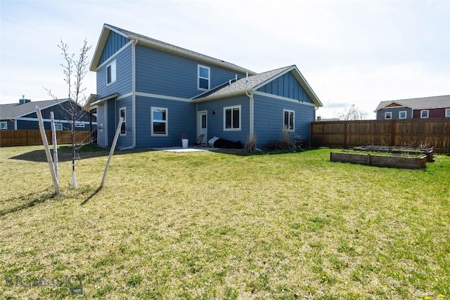 rear view of house with a yard, board and batten siding, a garden, and a fenced backyard