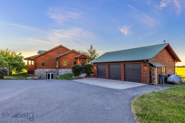 480 Moose Crossing Rd, Gallatin Gateway, MT 59730 - property exterior at dusk featuring a garage, stone siding, and a metal roof