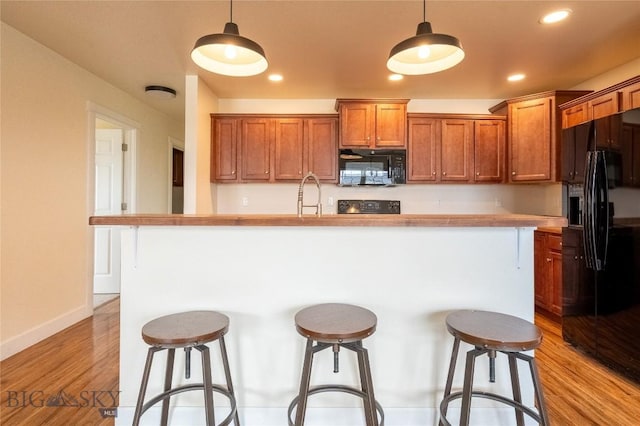 2300 Sturnella Ln, Belgrade, MT 59714 - kitchen with black appliances, a breakfast bar area, hanging light fixtures, an island with sink, and recessed lighting