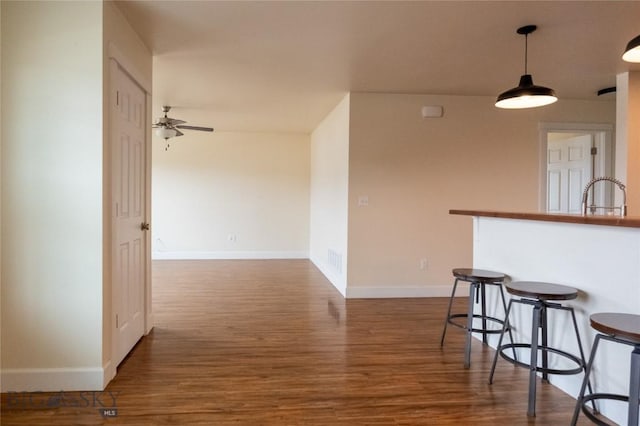 2300 Sturnella Ln, Belgrade, MT 59714 - kitchen featuring a ceiling fan, dark wood-style floors, a kitchen bar, baseboards, and a sink