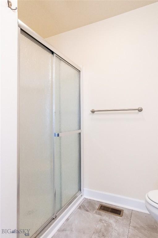 2300 Sturnella Ln, Belgrade, MT 59714 - bathroom featuring baseboards, a stall shower, and toilet