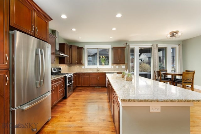 2026 Southbridge, Bozeman, MT 59718 - kitchen with appliances with stainless steel finishes, wall chimney exhaust hood, a kitchen island, light wood-style floors, and recessed lighting