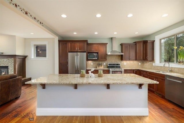 2026 Southbridge, Bozeman, MT 59718 - kitchen with appliances with stainless steel finishes, wall chimney exhaust hood, a sink, a kitchen breakfast bar, and tasteful backsplash